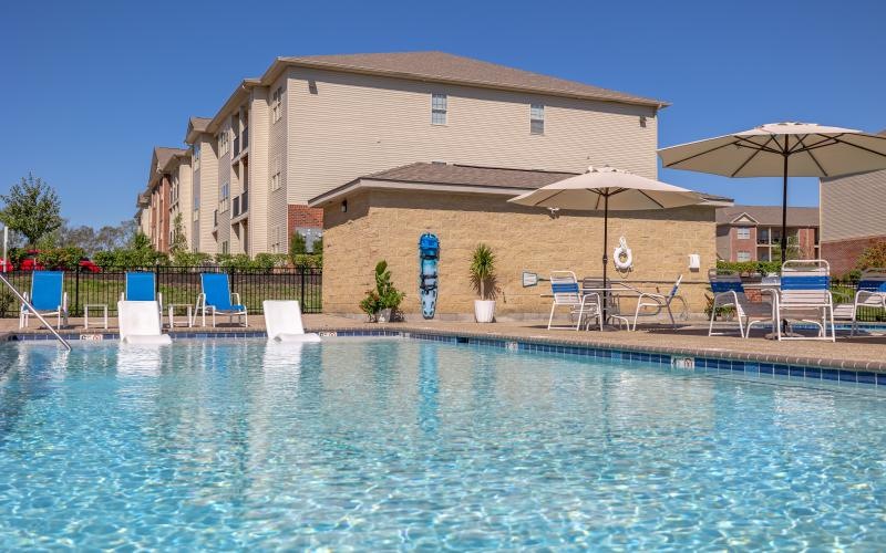 a pool with chairs and umbrellas by a building